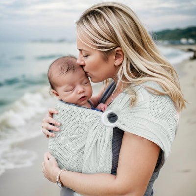 sling bebe gris clair maman embrasse nouveau-né plage